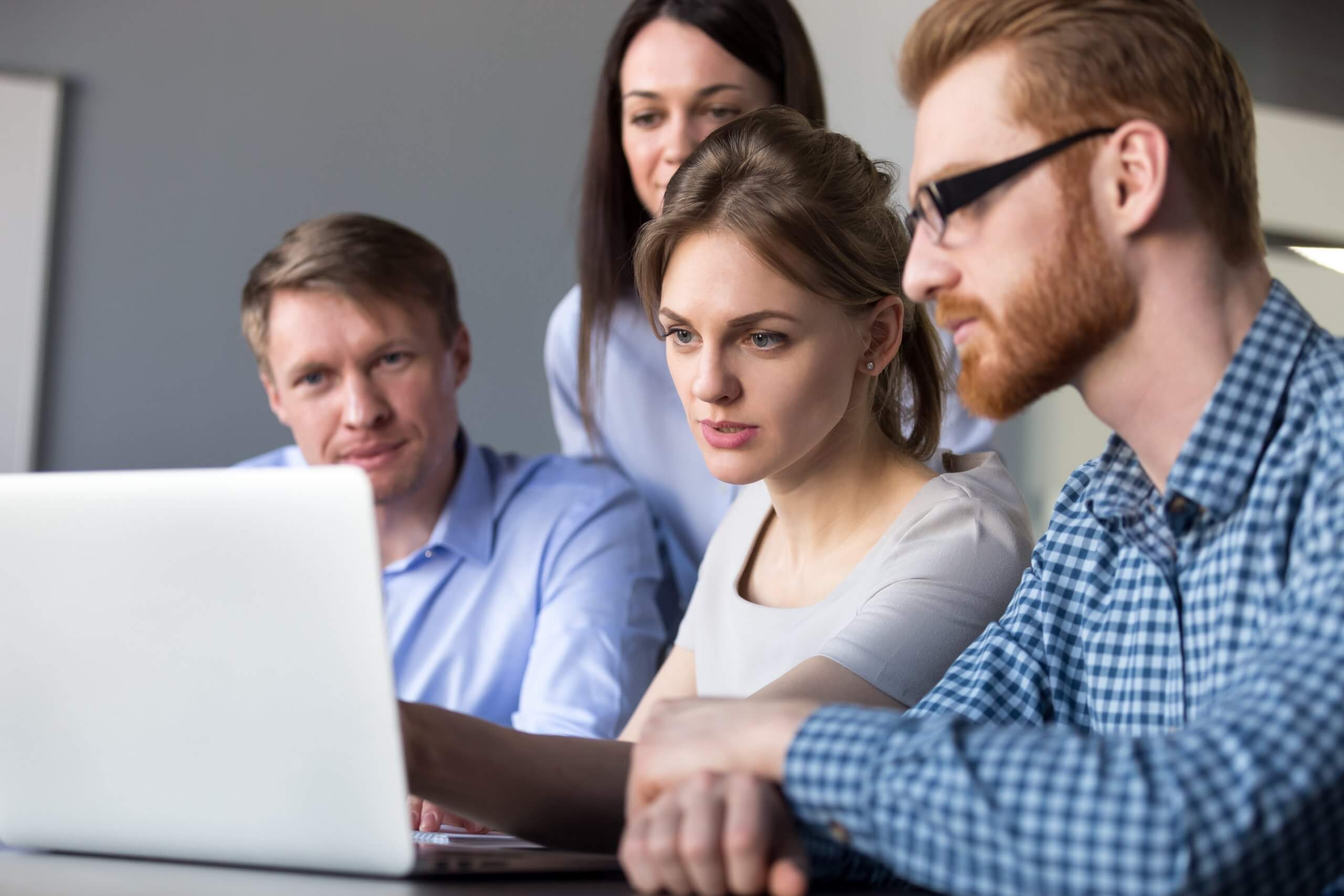 Zwei Frauen und zwei Männer schauen auf einen Monitor